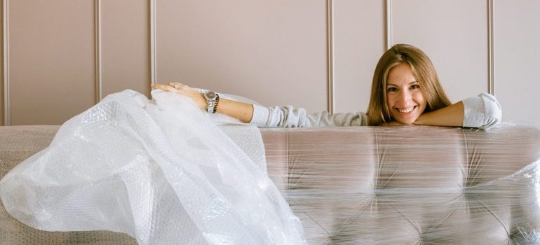 A woman next to a shrink wrapped sofa